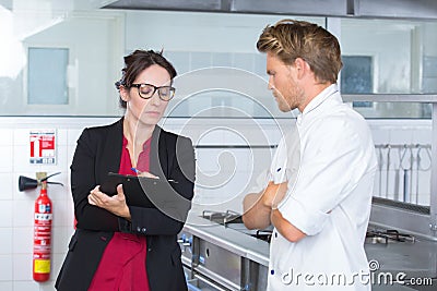 Female inspector in restaurant kitchen with chef Stock Photo