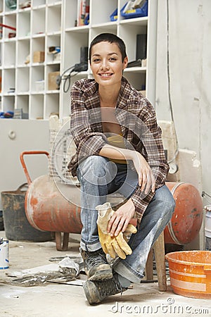 Female Interior Decorator Sitting On Stool In Work Site Stock Photo