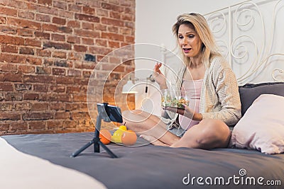 Female internet influencer pregnant girl streaming, joking with her followers, and explaining her plant-based diet Stock Photo