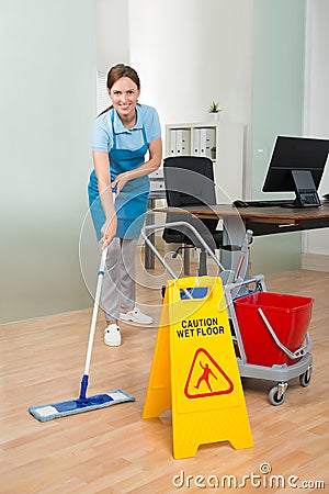 Female Janitor Cleaning Hardwood Floor In Office Stock Photo