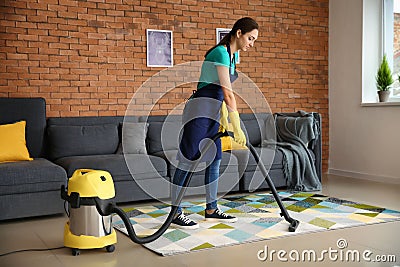 Female janitor hoovering carpet in flat Stock Photo