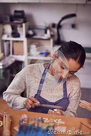 Female Jeweller At Bench Working On Ring With File In Studio Stock Photo