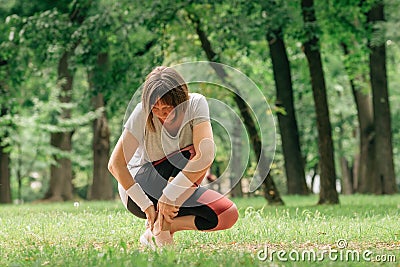 Female jogger with painful ankle injury during park jogging activity Stock Photo