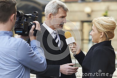 Female Journalist With Microphone Interviewing Businessman Stock Photo