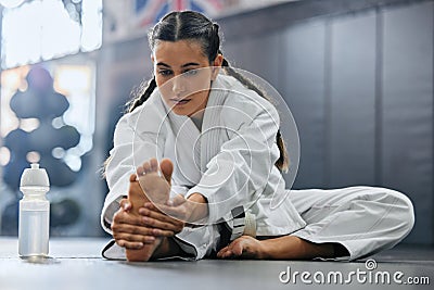 . Female karate school student doing a warmup, stretch or exercise with serious, determine and focus before workout Stock Photo