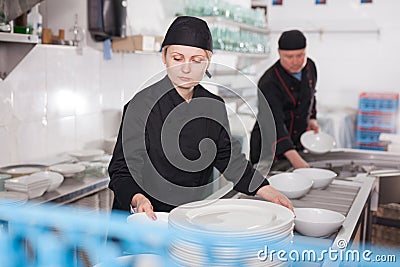 Female kitchen worker arranging cleaned dishes Stock Photo