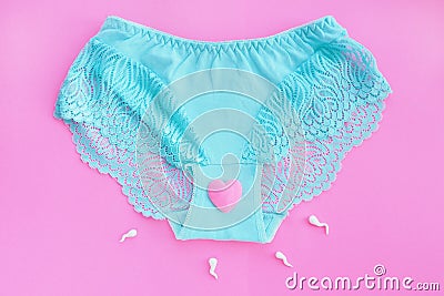 Female lace blue panties with a pink heart and spermatozoa on a pink background. Stock Photo