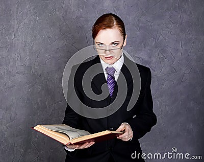 Female lawyer reads a big book with serious expression, woman in a man`s suit, tie and glasses Stock Photo