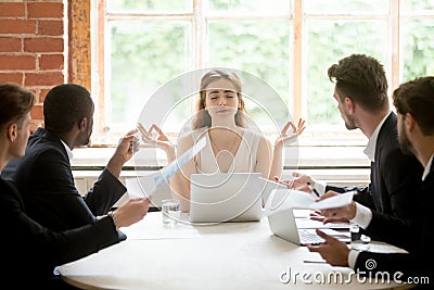 Female leader meditating ignoring angry coworkers Stock Photo