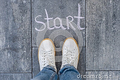 Female legs shod in white sneakers and the word start Stock Photo