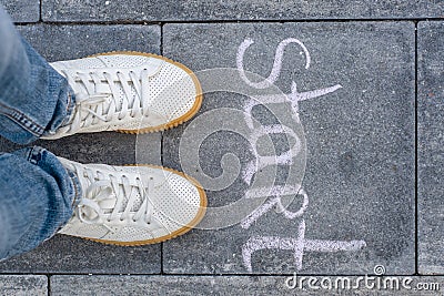 Female legs shod in white sneakers and the word start Stock Photo
