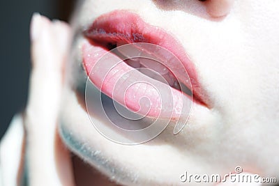 Female lips with beautiful shimmery pink gloss, closeup part of young face with fingers Stock Photo