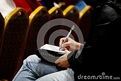 Female Listen to the Sermon and Writting Something on the Paper Stock Photo