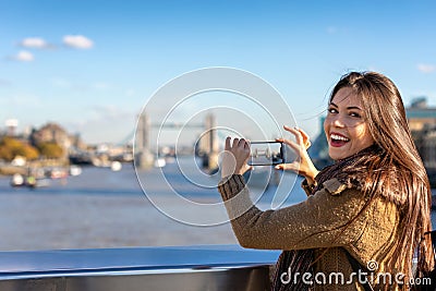 Female London tourist is taking pictures of the Tower Bridge Stock Photo