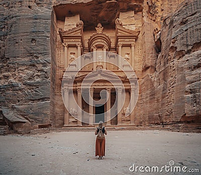 Female in a long orange skirt standing in front of the historic Petra Wadi in Jordan Editorial Stock Photo