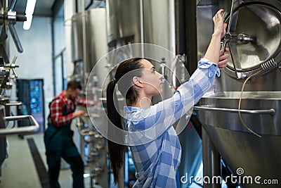 Female maintenance worker examining brewery machine Stock Photo