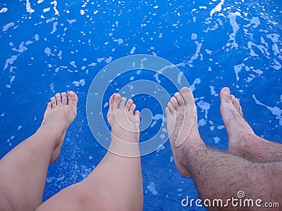 Female and male feet above the blue sea water, summer Stock Photo