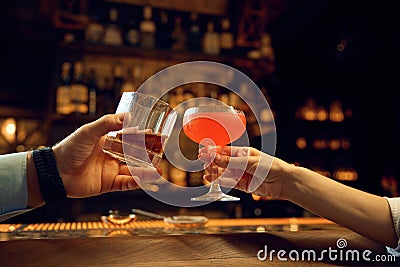 Female and male hands clinking glasses with alcoholic drinks closeup Stock Photo