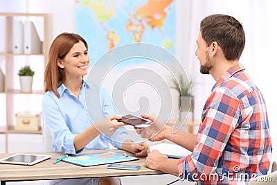 Female manager giving passport with ticket to client Stock Photo