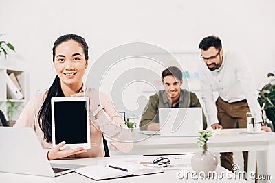 Female manager holding digital tablet with blank screen with male coworkers Stock Photo