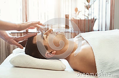 Female masseur doing head massage to man Stock Photo