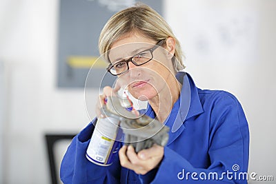 Female mechanic spraying rus releasing agent on part Stock Photo