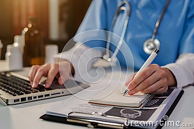 Doctor, physician or practitioner in lab room writing on blank notebook and work on laptop computer. Stock Photo