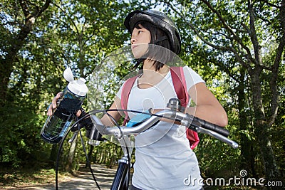 female mountain biker drinking water in forest Stock Photo