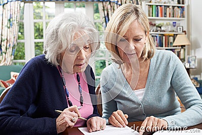 Female Neighbor Helping Senior Woman To Complete Form Stock Photo