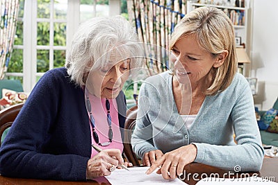 Female Neighbor Helping Senior Woman To Complete Form Stock Photo