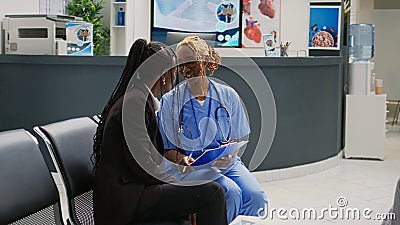 Female nurse consulting young woman in hospital waiting area Stock Photo