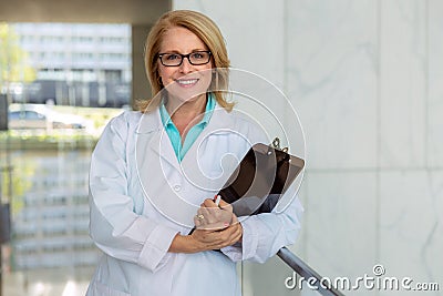 Female nurse, doctor, health care practitioner, standing lifestyle working portrait in hospital hallway, smiling and cheerful Stock Photo