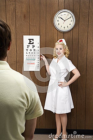 Female nurse pointing out eye chart to man. Stock Photo