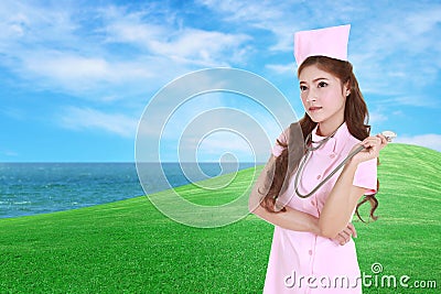 Female nurse with stethoscope with green grass field Stock Photo