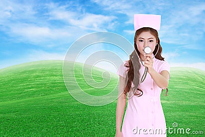 Female nurse with stethoscope with green grass field Stock Photo