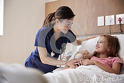 Female Nurse Visiting Girl Lying In Hospital Bed Hugging Teddy Bear Stock Photo