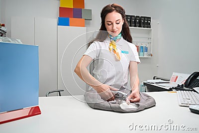 Female operator of laundry service applying tag with info on garment Stock Photo