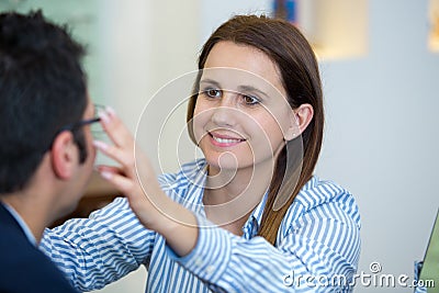 Female optician fitting glasses onto male patient Stock Photo