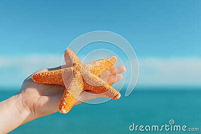 Female palm holding starfish in front of blue sky and sea Stock Photo