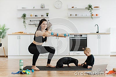 Female parent exercising near infant with Dachshund at home Stock Photo
