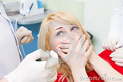 Female patient in dentist office afraid of doctor, procedure Stock Photo