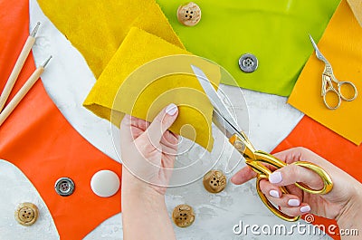 Female person making color genuine leather wallet with scissors cuts the segment Leather at atelier. Concept of Stock Photo