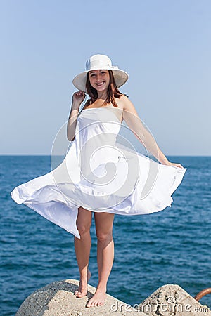 Female person in white hat and white sarong posing against sea Stock Photo