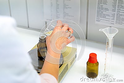 Female pharmacist mixing chemical liquids on medical scales in a laboratory Stock Photo