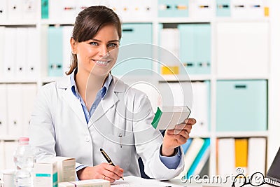 Female pharmacist sat at desk writing notes Stock Photo