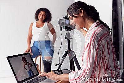 Female Photographer In Digital Studio Shooting Images On Camera Tethered To Laptop Computer Stock Photo