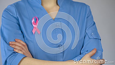 Female physician with pink ribbon in blue uniform, breast cancer awareness Stock Photo