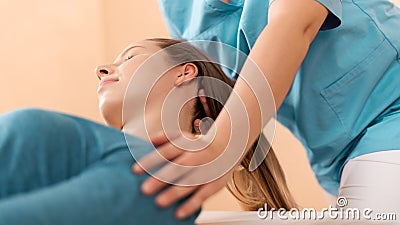 Female physiotherapist or a chiropractor adjusting patients neck. Physiotherapy, rehabilitation concept. Side view cropped shot. Stock Photo