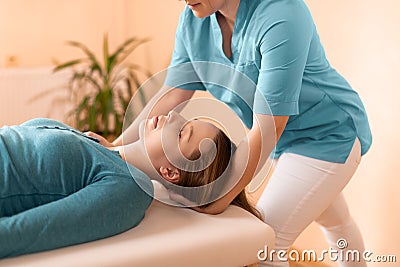 Female physiotherapist or a chiropractor adjusting patients neck. Physiotherapy, rehabilitation concept. Side view cropped shot. Stock Photo
