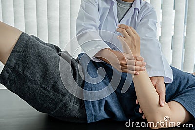 Female physiotherapists provide assistance to male patients with elbow injuries examine patients in rehabilitation centers. Stock Photo
